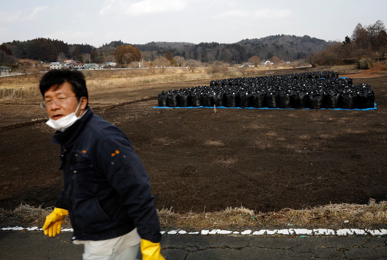 Sakae Kato walks past black bags containing contaminated soil from the fallout of the Fukushima nuclear plant, in a restricted zone in Namie, Fukushima Prefecture, Japan, February 21, 2021. Kato looks after 41 cats in his home and another empty building on his property. A decade ago, Kato stayed behind to rescue cats abandoned by neighbours who fled the radiation clouds belching from the nearby Fukushima nuclear plant. He won't leave. I don't want to leave, I like living in these mountains,