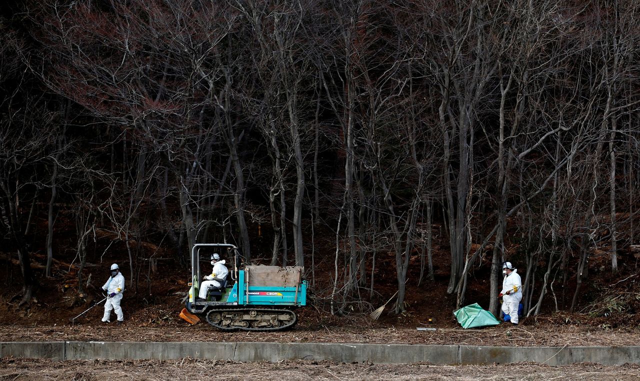 FILE PHOTO: Decontamination workers wearing protective suits and masks, remove radiated soil and leaves from a forest in Tomioka town, Fukushima prefecture, near Tokyo Electric Power Co's (TEPCO) tsunami-crippled Fukushima Daiichi nuclear power plant February 24, 2015. REUTERS/Toru Hanai