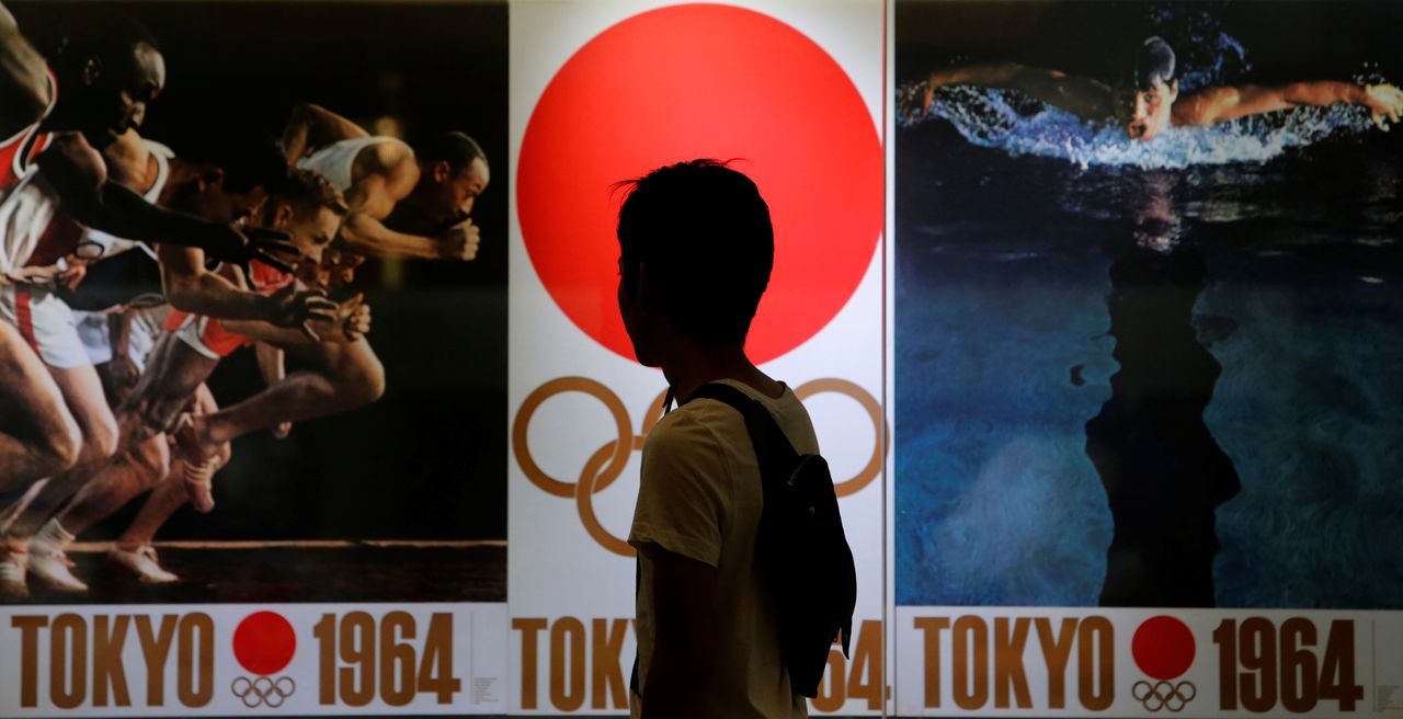 FILE PHOTO: A pedestrian looks at pictures of the 1964 Summer Olympics in Tokyo, part of a photo exhibition inside the Tokyo train station building September 8, 2013. REUTERS/Yuya Shino/File Photo