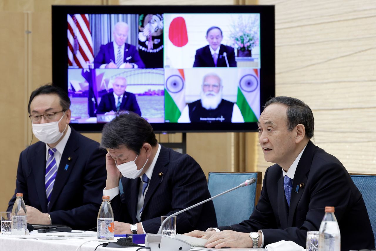 Yoshihide Suga, Japan's Prime Minister, speaks while a monitor displays U.S. President Joe Biden, Australia's Prime Minister Scott Morrison and India's Prime Minister Narendra Modi, during the virtual Quadrilateral Security Dialogue (Quad) meeting at his official residence in Tokyo, Japan, on Friday, March 12, 2021. Kiyoshi Ota/Pool via REUTERS