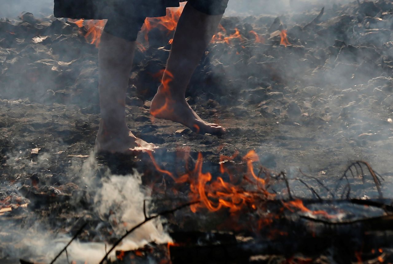 A womaN walks across smoldering hot ground at the fire-walking festival, called hiwatari matsuri in Japanese, at Mt.Takao in Tokyo, Japan, March 14, 2021. REUTERS/Kim Kyung-Hoon