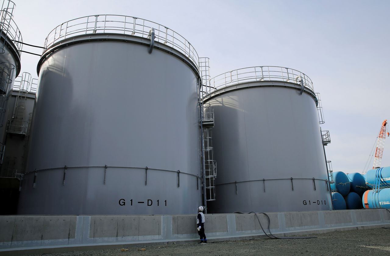 FILE PHOTO: An employee of Tokyo Electric Power Co. (TEPCO) looks up at a tank reserved for storing treated water at the tsunami-crippled Fukushima Daiichi nuclear power plant in Okuma town, Fukushima prefecture, Japan March 1, 2021. REUTERS/Sakura Murakami