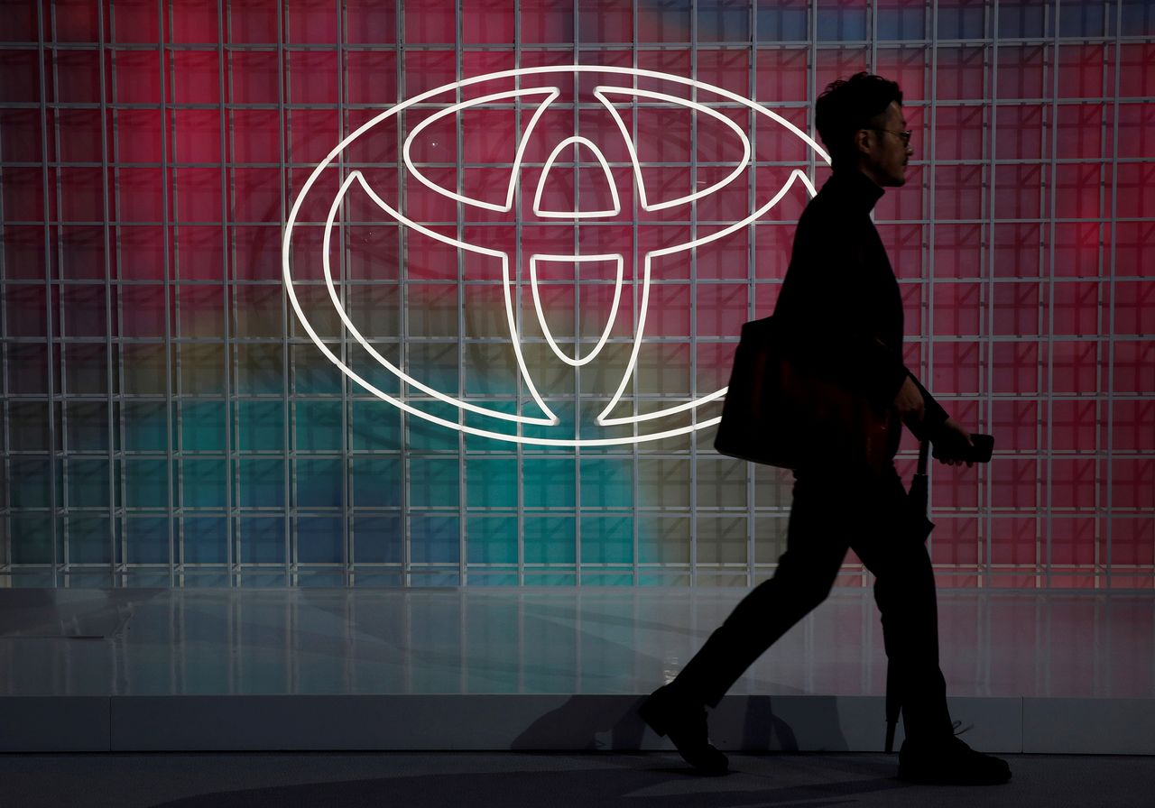FILE PHOTO: A man walks past a Toyota logo at the Tokyo Motor Show, in Tokyo, Japan October 24, 2019. REUTERS/Edgar Su/File Photo