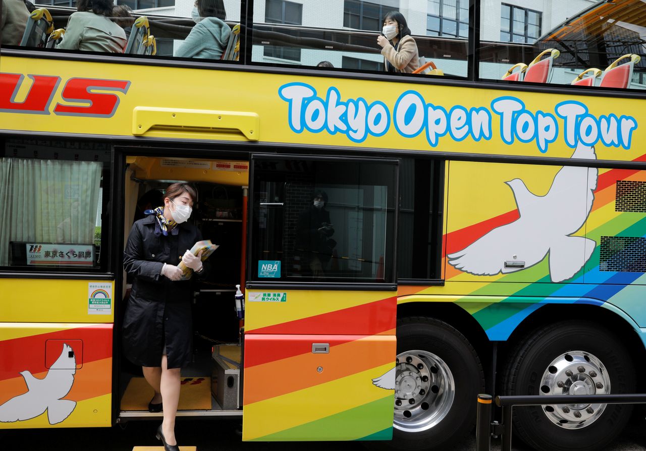 A tour guide of Hato Bus Co. works at an open-top sightseeing bus as the tour service resumed after Japan's government lifted the coronavirus disease (COVID-19) state of emergency in the Tokyo area, in Tokyo, Japan March 22, 2021. REUTERS/Androniki Christodoulou NO RESALES. NO ARCHIVES