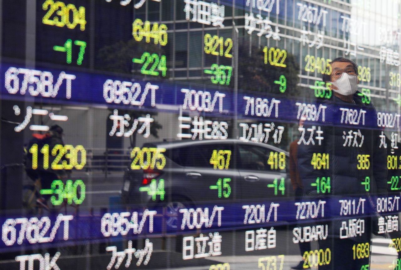 FILE PHOTO: A man is reflected on a stock quotation board in Tokyo, Japan February 26, 2021. REUTERS/Kim Kyung-Hoon