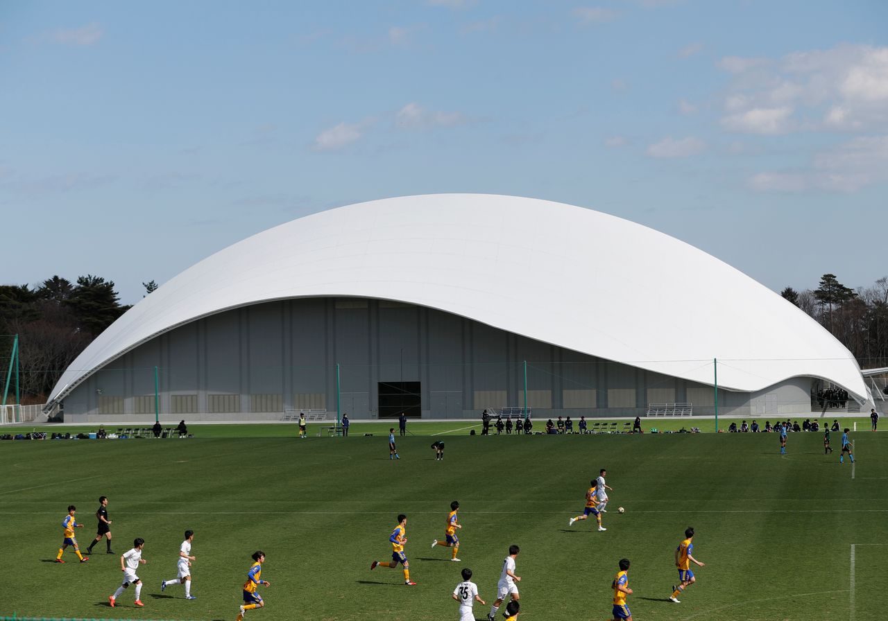 High school students play soccer game in front of a soccer training facility where torch relay of the Tokyo 2020 Olympic Games is set to begin at the J-Village training center in Naraha, Fukushima prefecture, Japan, March 23, 2021. REUTERS/Kim Kyung-Hoon