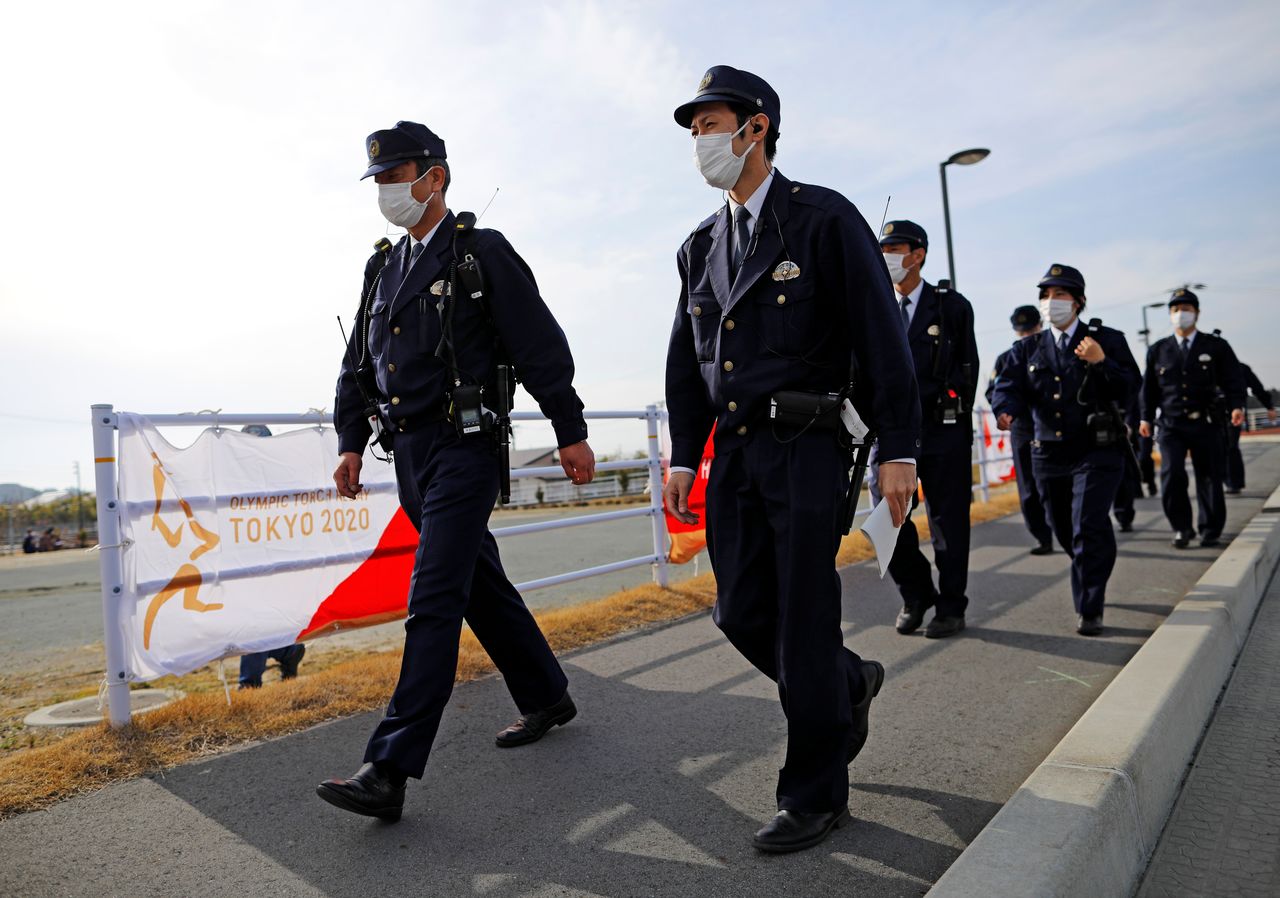 Police officers proceed to their stations on the first day of the Tokyo 2020 Olympic torch relay in Naraha, Fukushima prefecture, Japan March 25, 2021. REUTERS/Issei Kato