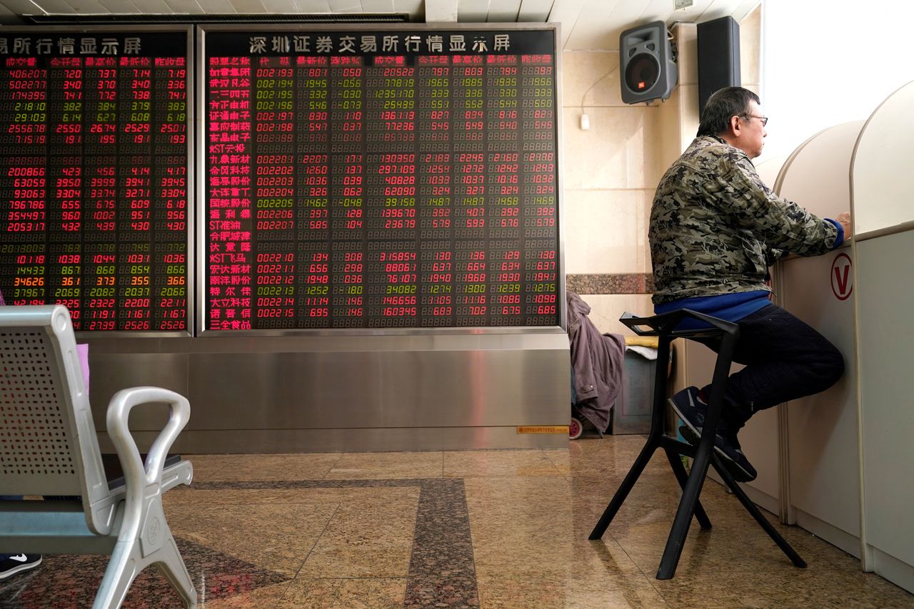 FILE PHOTO: An investor sits next to a stock quotation board at a brokerage office in Beijing, China January 3, 2020. REUTERS/Jason Lee
