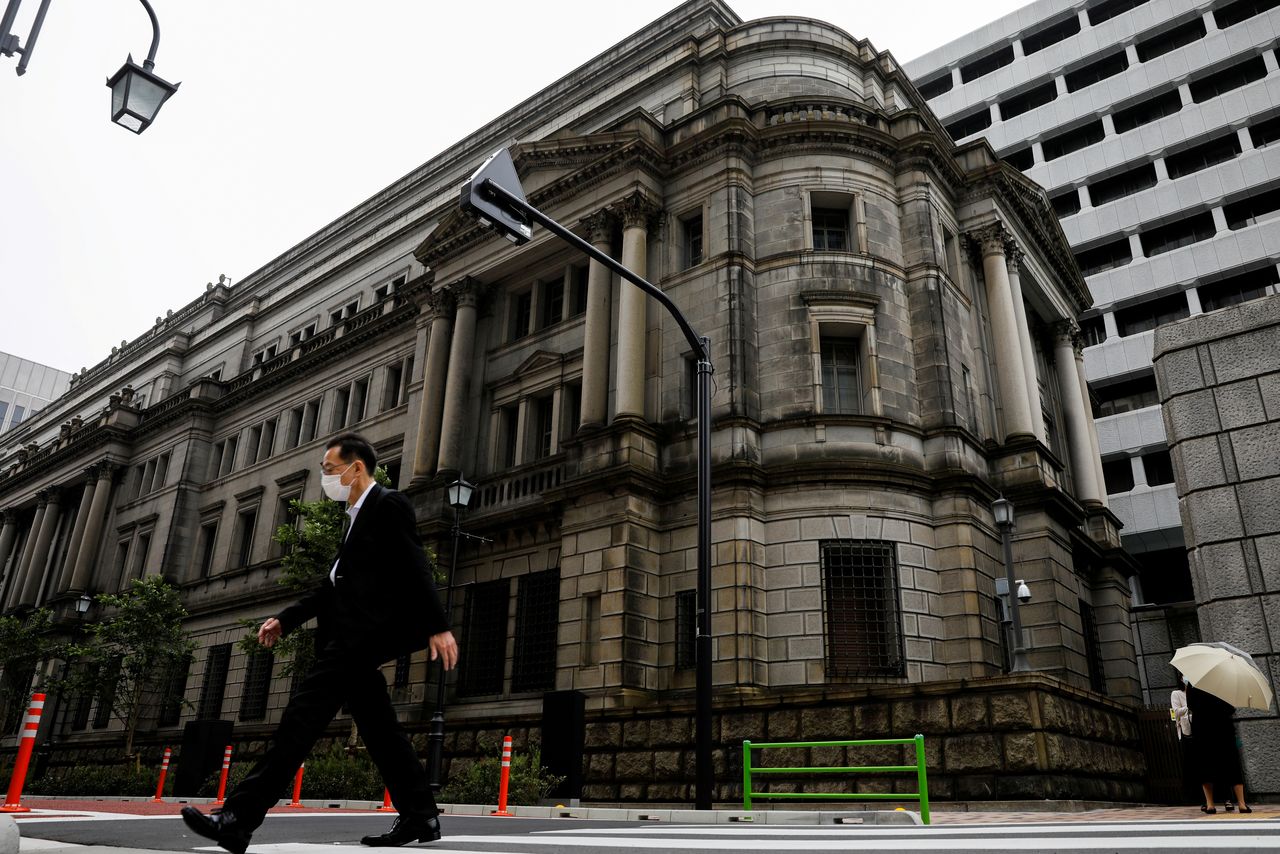 FILE PHOTO: A man wearing a protective mask walks past the headquarters of the Bank of Japan in Tokyo, Japan, May 22, 2020.REUTERS/Kim Kyung-Hoon