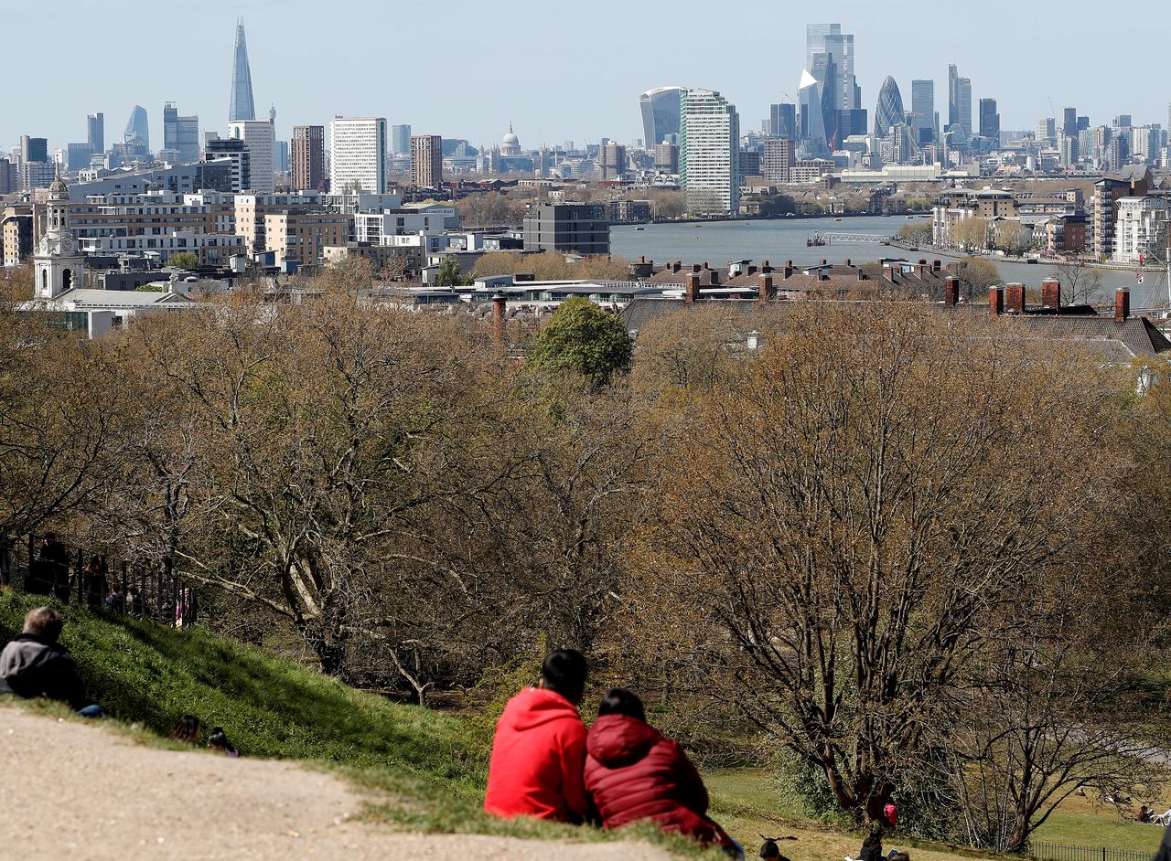 FILE PHOTO: Visitors to Greenwich Park sit and look towards the City of London as lockdown restrictions are eased amidst the spread of the coronavirus disease (COVID-19) pandemic in London, Britain, April 25, 2021. REUTERS/Peter Nicholls