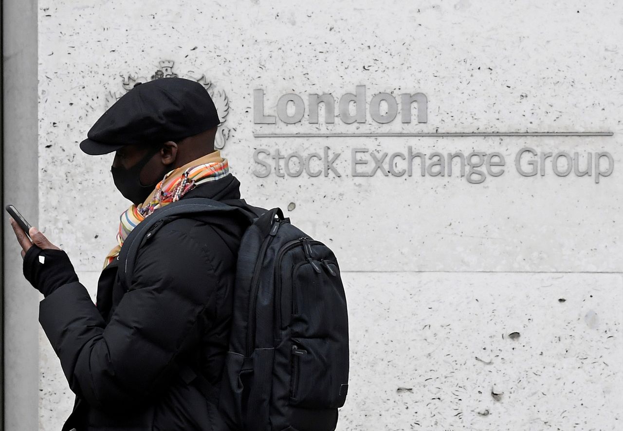 FILE PHOTO: A man wearing a protective face mask walks past the London Stock Exchange Group building in the City of London financial district, whilst British stocks tumble as investors fear that the coronavirus outbreak could stall the global economy, in London, Britain, March 9, 2020. REUTERS/Toby Melville