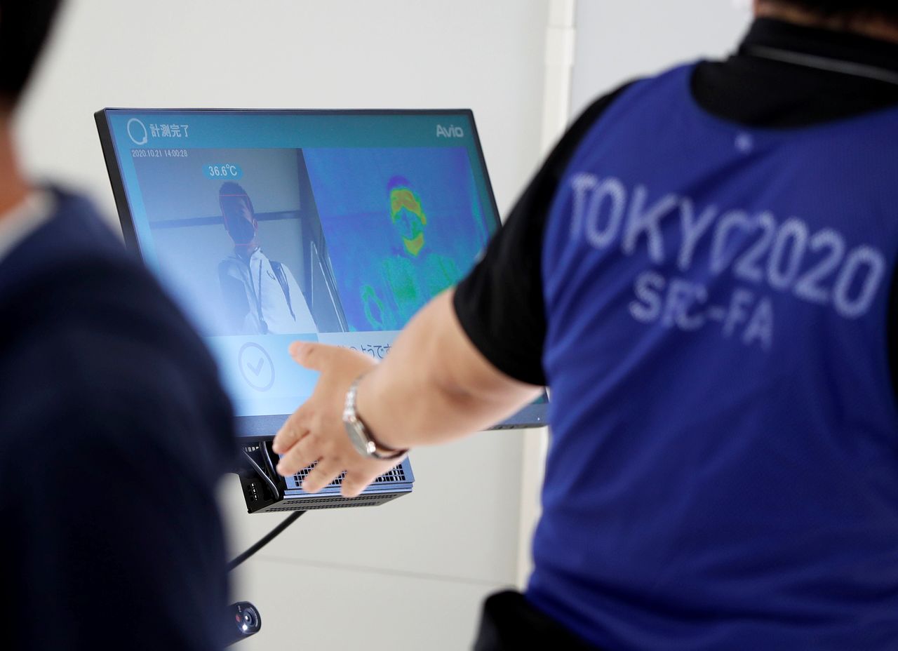 FILE PHOTO: A screen displays body temperature check results during a test for games spectators, hosted by Tokyo Organising Committee of the Olympic and Paralympic Games, ahead of the summer games that have been postponed to 2021 due to the coronavirus disease outbreak, at Tokyo Big Sight, Japan October 21, 2020. REUTERS/Issei Kato