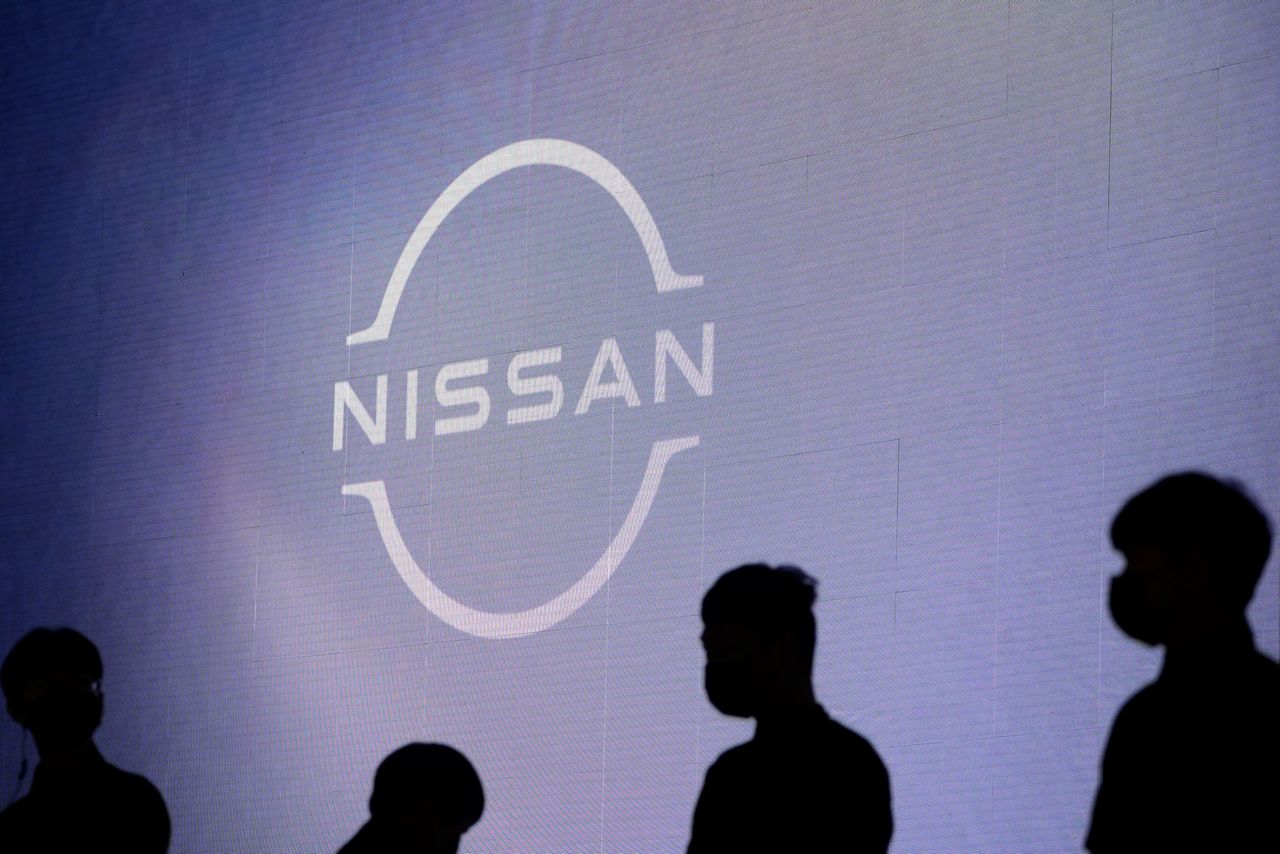 FILE PHOTO: People stand near the Nissan logo during a media day for the Auto Shanghai show in Shanghai, China April 20, 2021. REUTERS/Aly Song