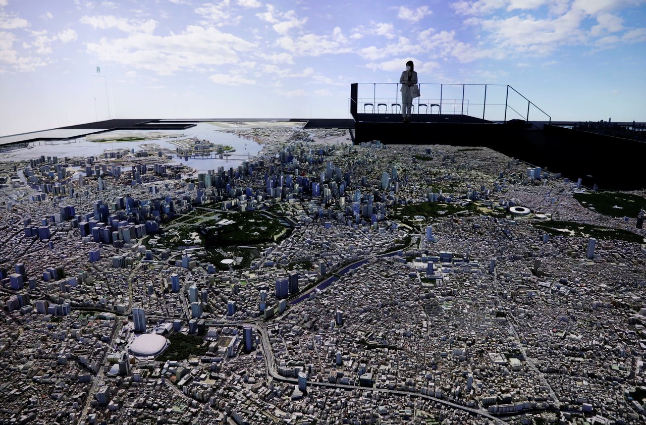 FILE PHOTO: Staff at Mori Building Urban Lab looks at a miniaturised 1:1000 scale version of Tokyo with projection mapping at its demonstration in Tokyo, Japan, April 26, 2021. REUTERS/Kim Kyung-Hoon