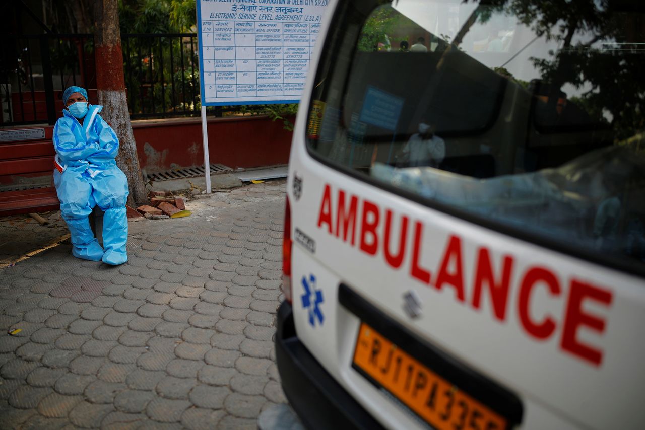 FILE PHOTO: A health worker rests as he sits next to his ambulance carrying a dead body of a victim who died due to the coronavirus disease (COVID-19), at a crematorium in New Delhi, India, May 10, 2021. REUTERS/Adnan Abidi