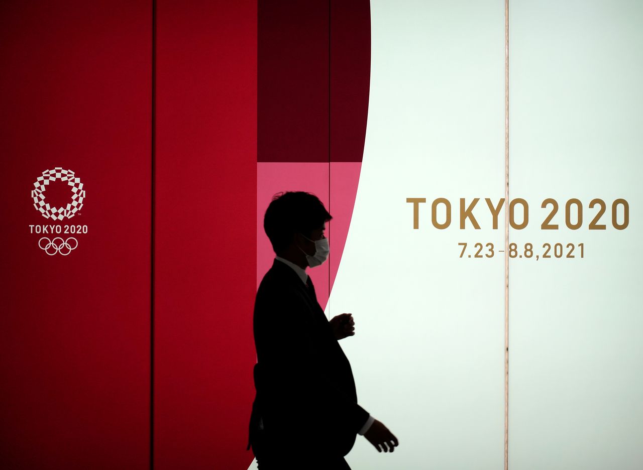 A man wearing a protective face mask walks by an advertising of Tokyo 2020 Olympic Games that have been postponed to 2021 due to the coronavirus disease (COVID-19) outbreak, in Tokyo, Japan May 14, 2021. REUTERS/Naoki Ogura