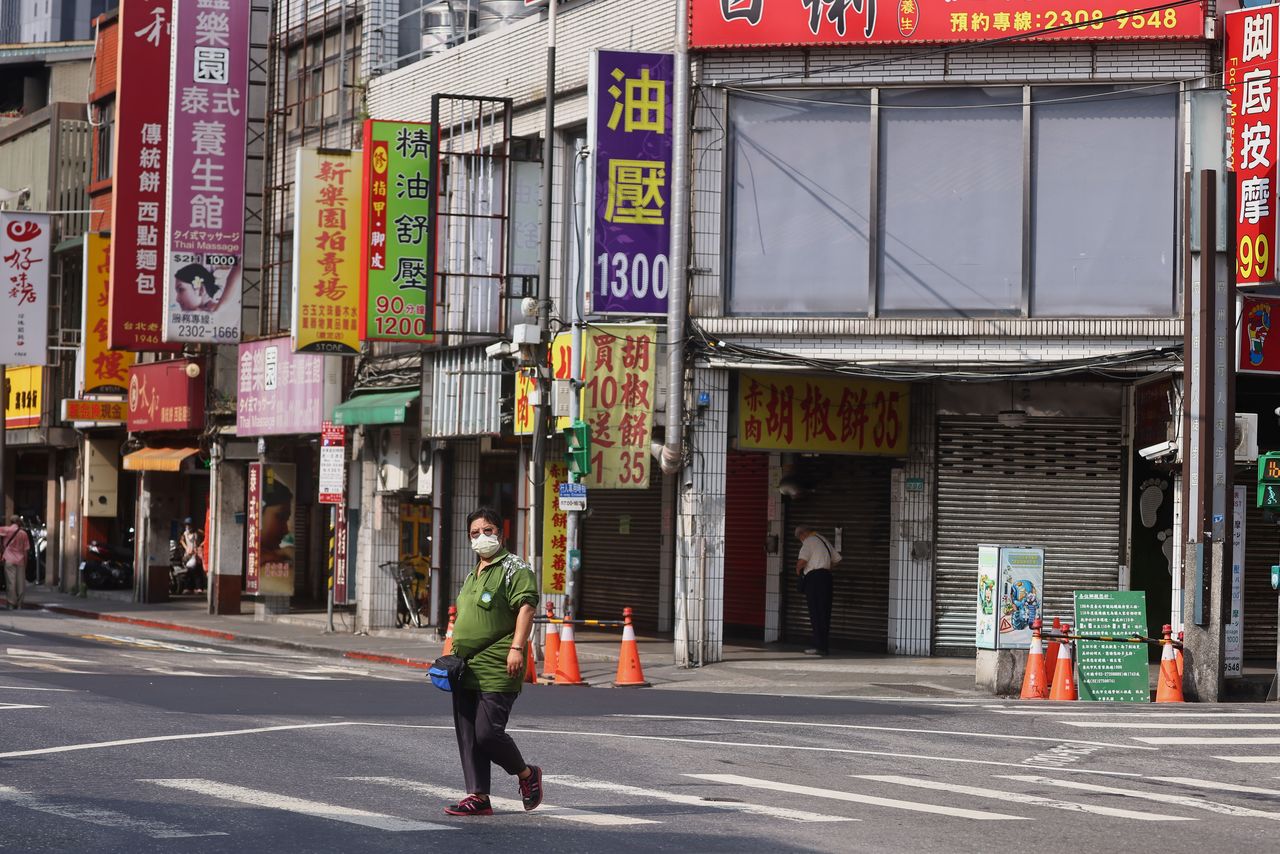 A woman wears a protective face mask while crossing a street in Wanhua district following a surge of coronavirus disease (COVID-19) infections in Taipei, Taiwan, May 19, 2021. REUTERS/Ann Wang