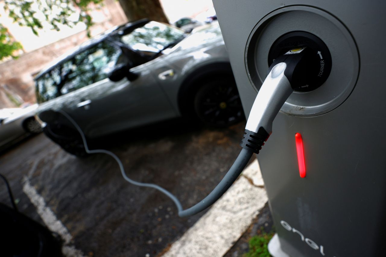 FILE PHOTO: An electric car is seen plugged in at a charging point for electric vehicles in Rome, Italy, April 28, 2021. REUTERS/Guglielmo Mangiapane