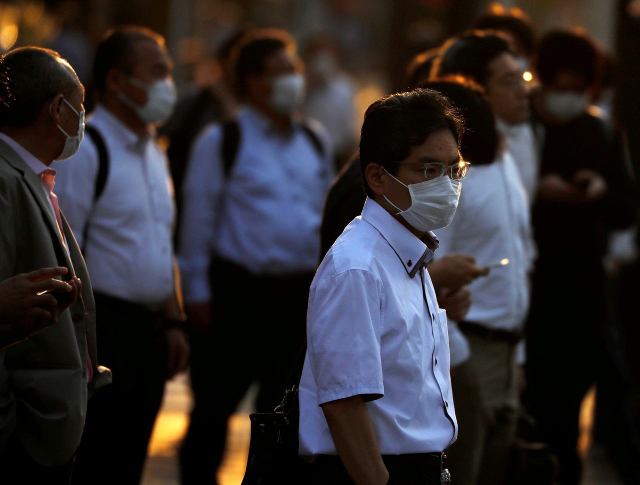 FILE PHOTO: Office workers wearing protective face masks walk to head home at sunset amid the coronavirus disease (COVID-19) outbreak, in Tokyo, Japan June 9, 2020. REUTERS/Issei Kato