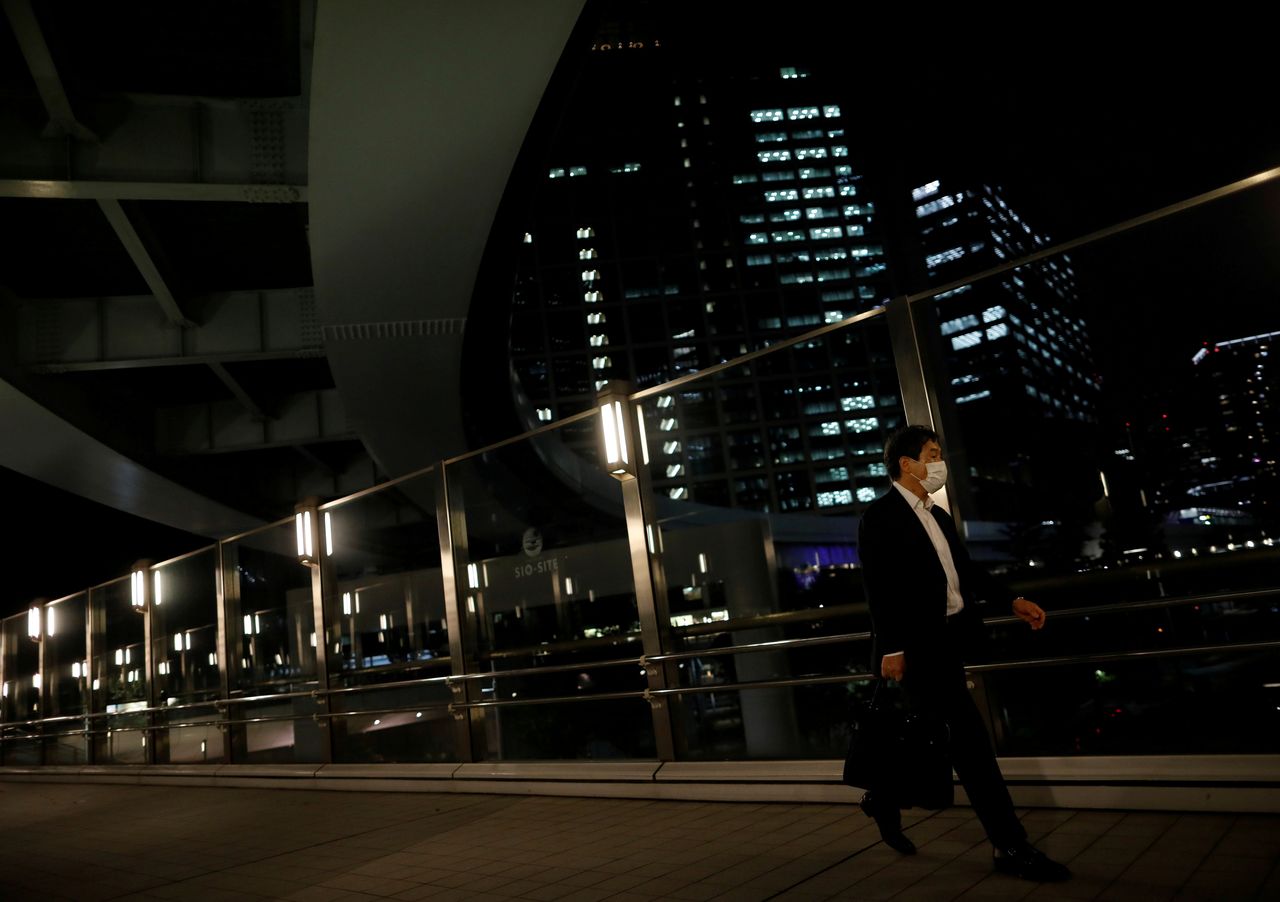 FILE PHOTO: A worker wearing a protective face mask walks past office buildings in the background, during the global outbreak of the coronavirus disease (COVID-19), in Tokyo, Japan June 2, 2020. Picture taken June 2, 2020. REUTERS/Issei Kato/File Photo