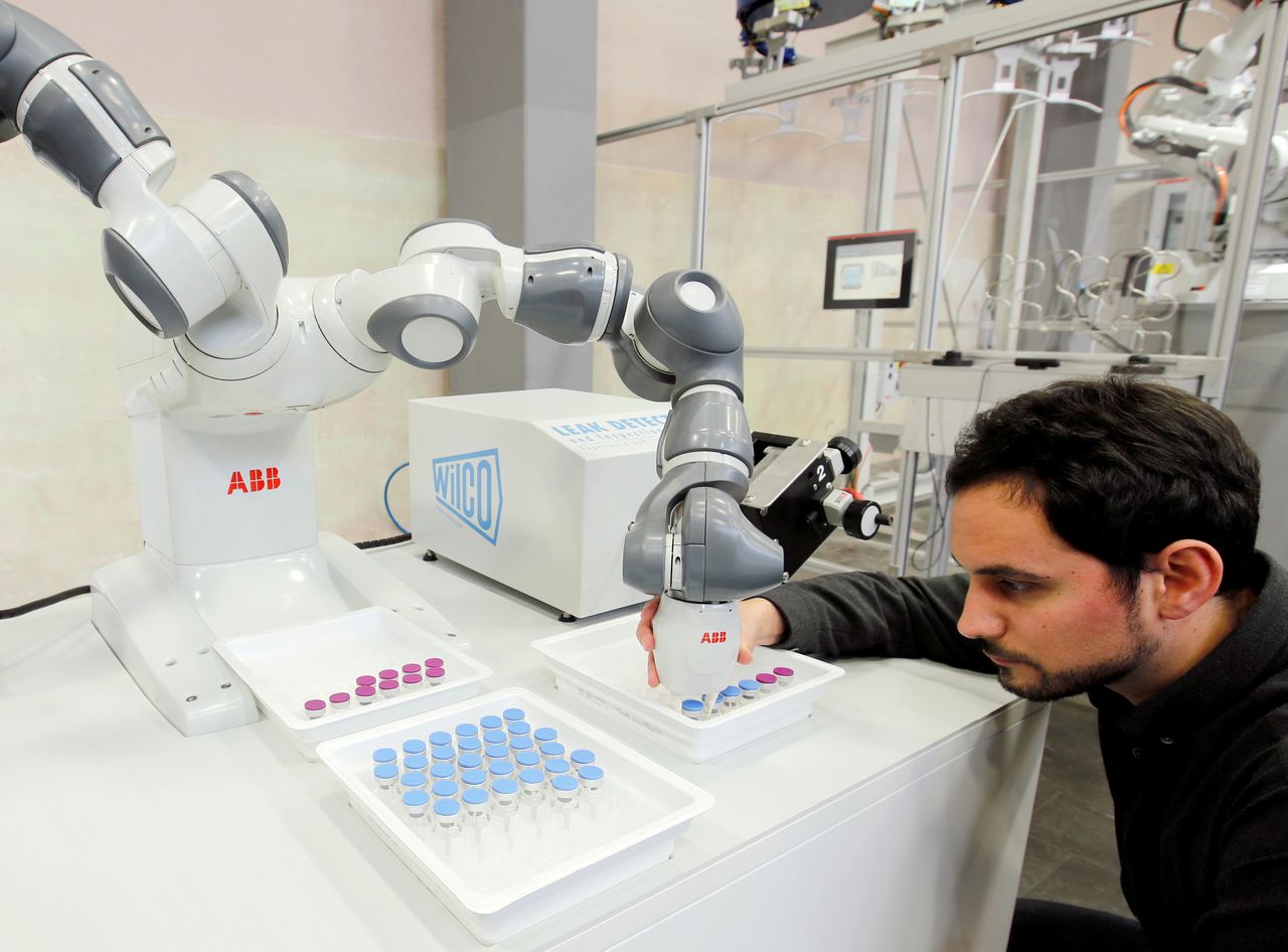 FILE PHOTO: Engineer Manel Trilla of Swiss power technology and automation group ABB adjusts an arm of a YuMi - IRB14000, a collaborative dual-arm industrial robot, of ABB Robotics at a plant in Baden, Switzerland February 7, 2019. REUTERS/Arnd Wiegmann/File Photo
