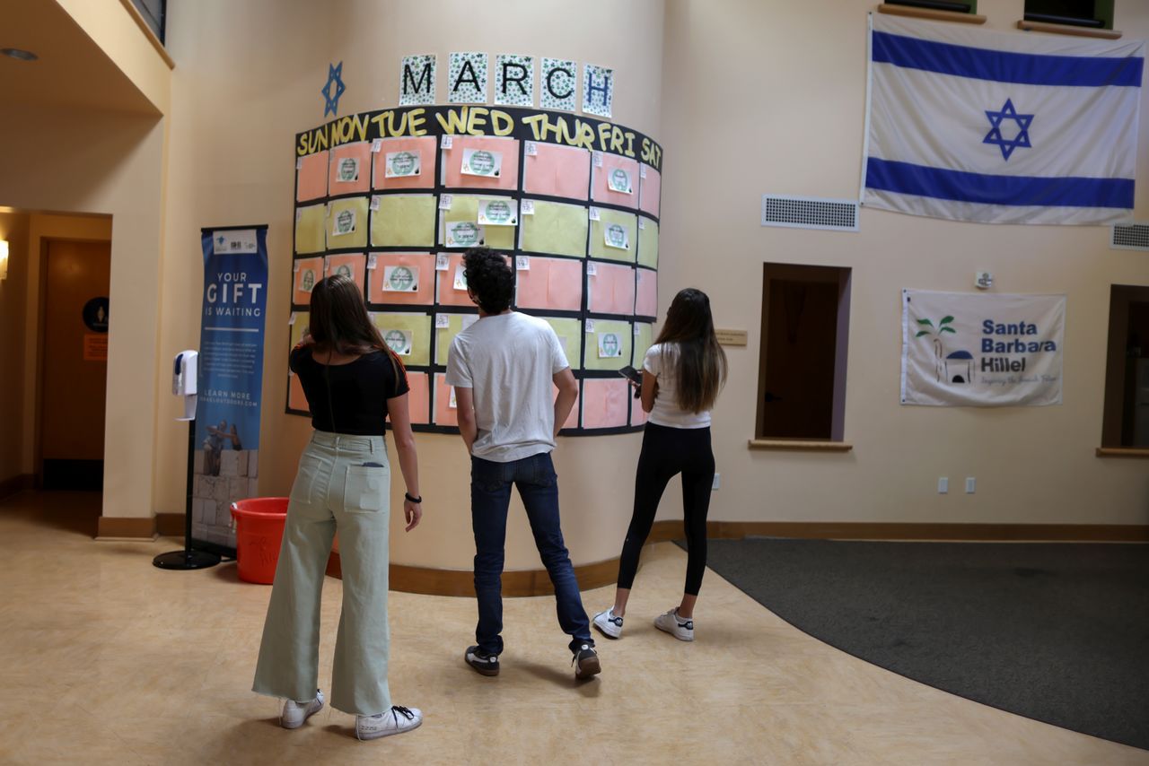 Students Tyler Barth, 21, Romi Benasuly, 20, and Lian Benasuly, 20, look at a pre-pandemic social calendar at Santa Barbara Hillel near the University of California, Santa Barbara (UCSB) campus in Isla Vista, California, U.S., May 24, 2021. REUTERS/Lucy Nicholson
