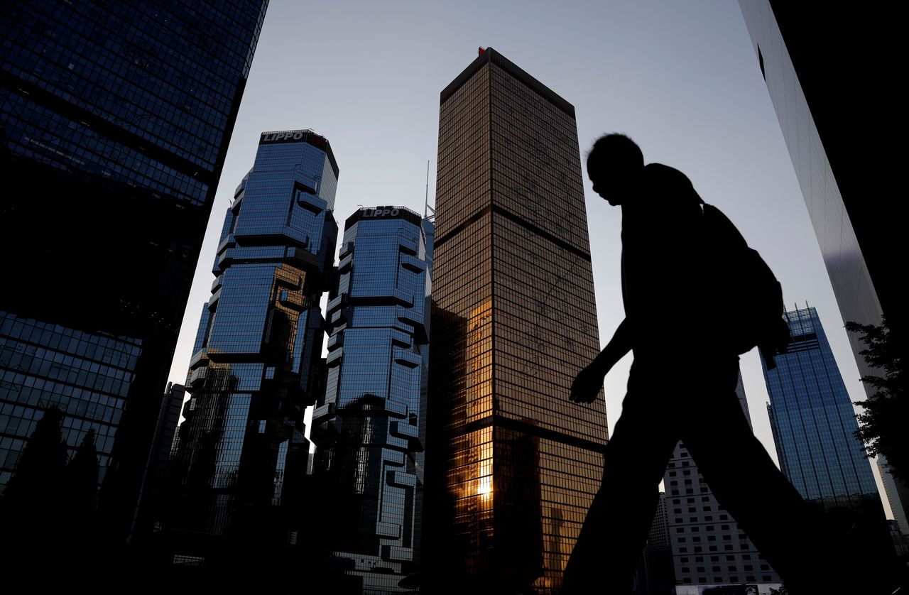 FILE PHOTO: A man walks past buildings at a business district in Hong Kong, China, November 4, 2019. REUTERS/Kim Kyung-Hoon
