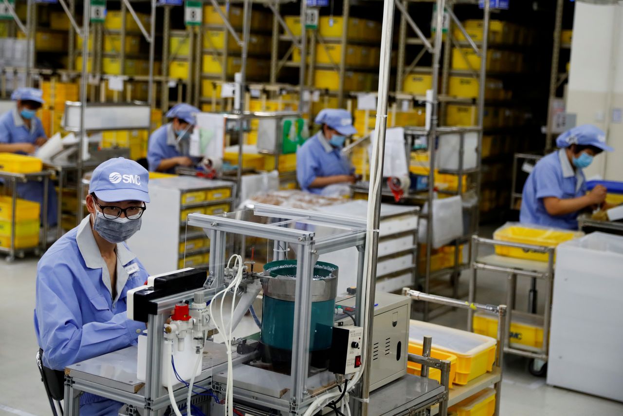 FILE PHOTO: Employees wearing face masks work at a factory of the component maker SMC during a government organised tour of its facility following the outbreak of the coronavirus disease (COVID-19), in Beijing, China May 13, 2020. REUTERS/Thomas Peter