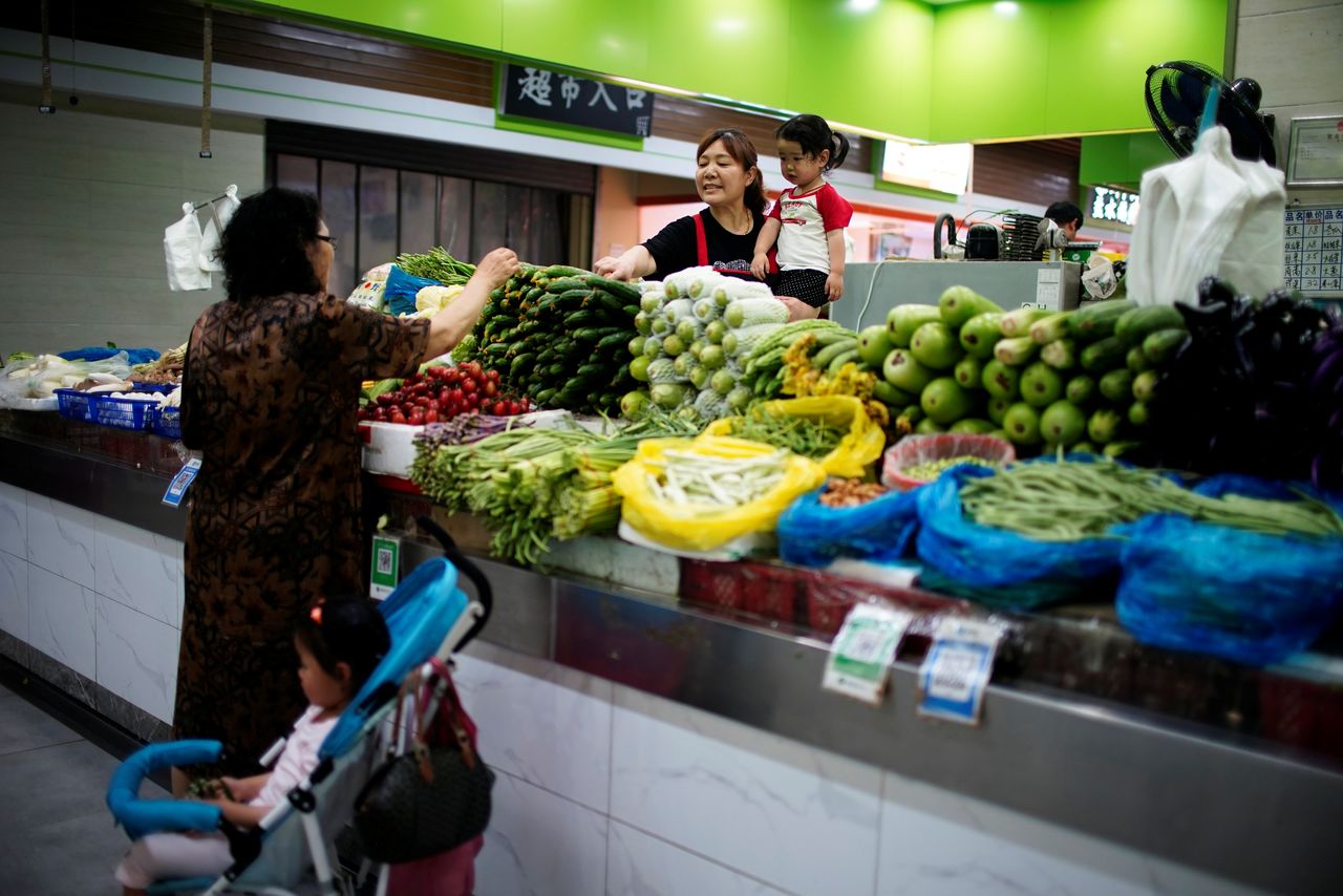 Two grandmothers with their granddaughter trade vegetables at a market on the outskirts of Shanghai, China June 3, 2021. REUTERS/Aly Song