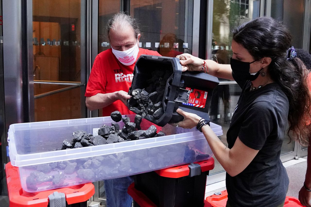 FILE PHOTO: People put coal in a container as they protest against BlackRock investing in coal and tar sands by blocking their front door with coal at their headquarters in the Manhattan borough of New York City, New York, U.S., May 25, 2021. REUTERS/Carlo Allegri/File Photo
