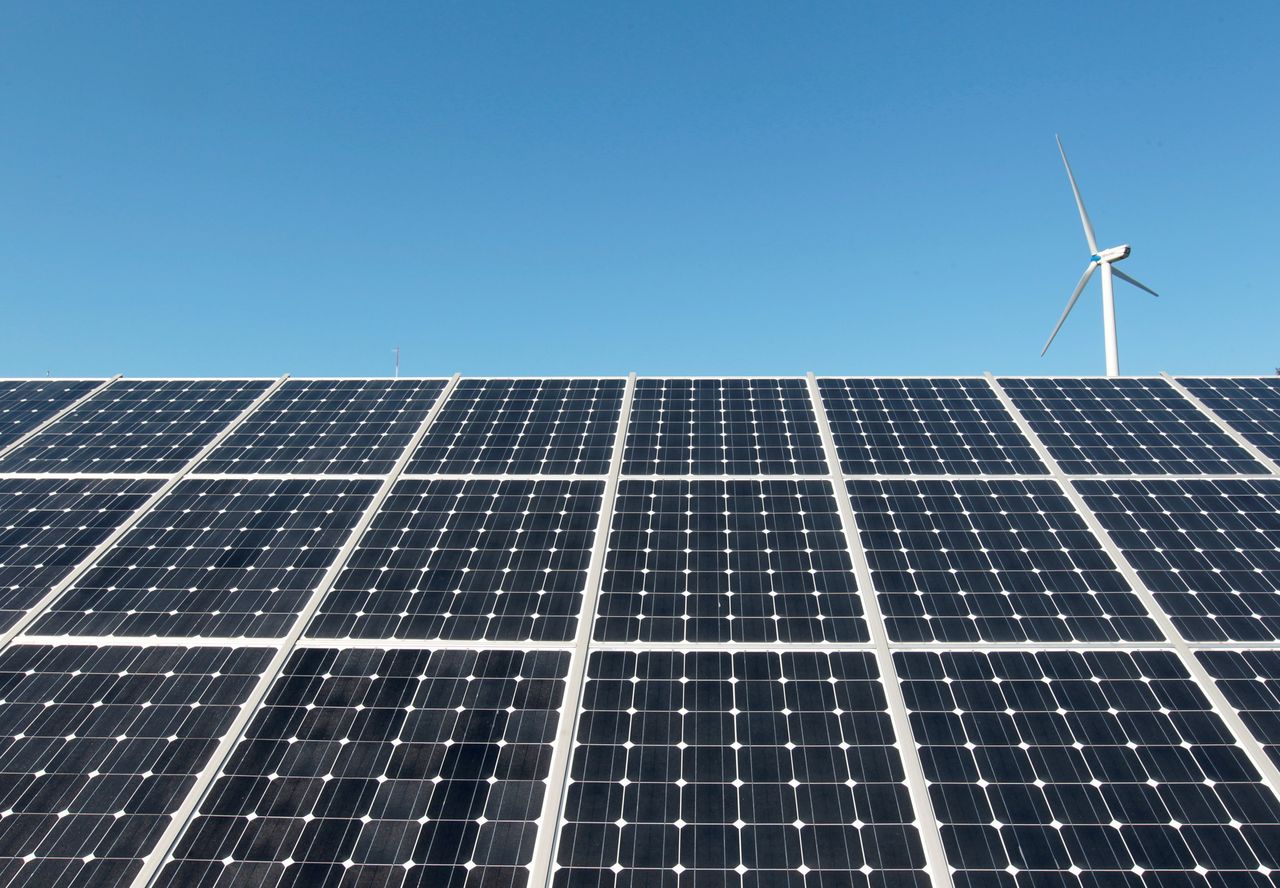 FILE PHOTO: A wind turbine is seen over the panels of a solar power plant of Korea South East Power Co. (KOSEP) in Incheon, in this file photo taken September 30, 2010. REUTERS/Jo Yong-Hak/File Photo