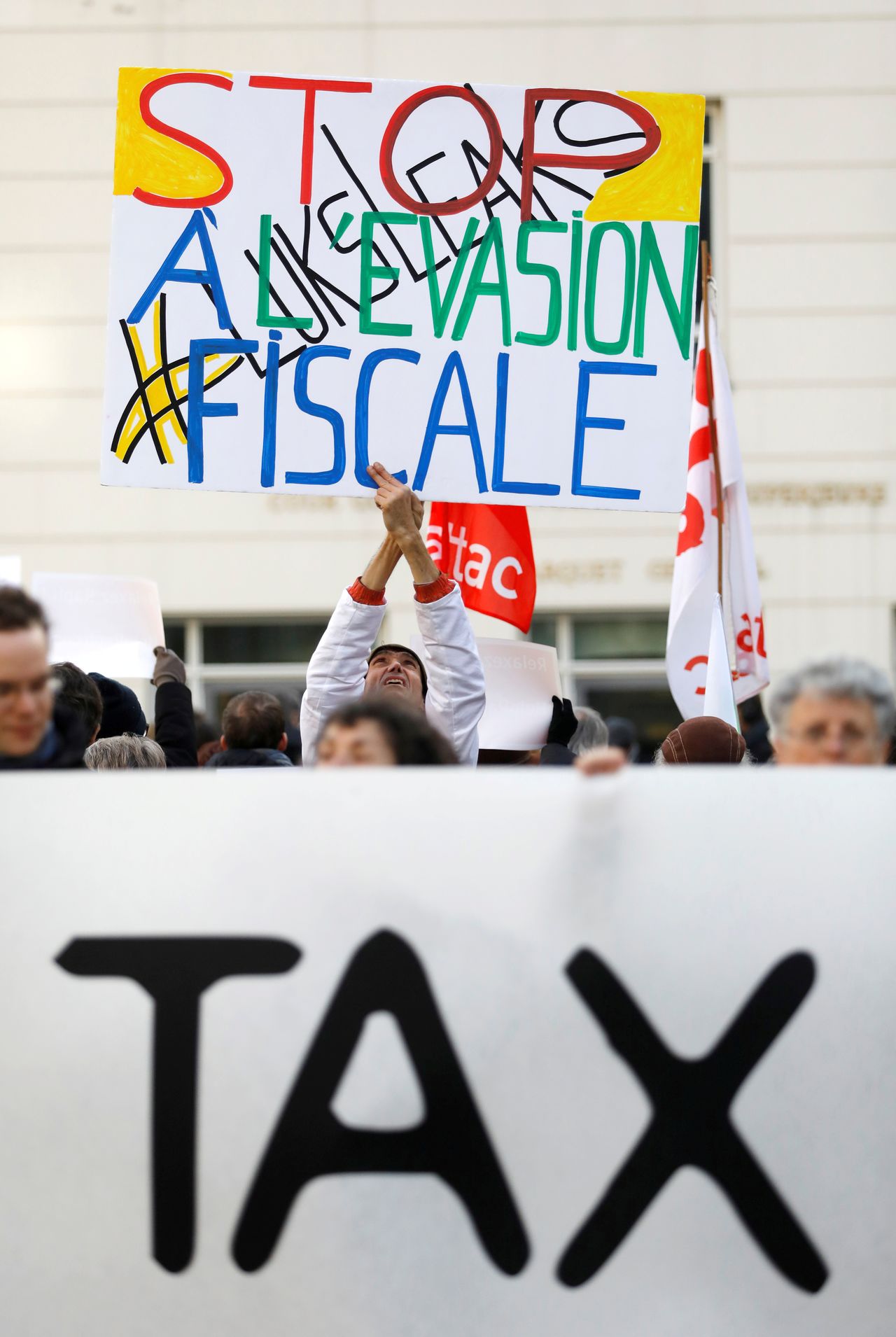 FILE PHOTO: A man holds a placard reading "Stop tax avoidance" during a protest outside the courthouse ahead of the LuxLeaks trial before an appeal court in Luxembourg, December 12, 2016. REUTERS/Yves Herman/File Photo