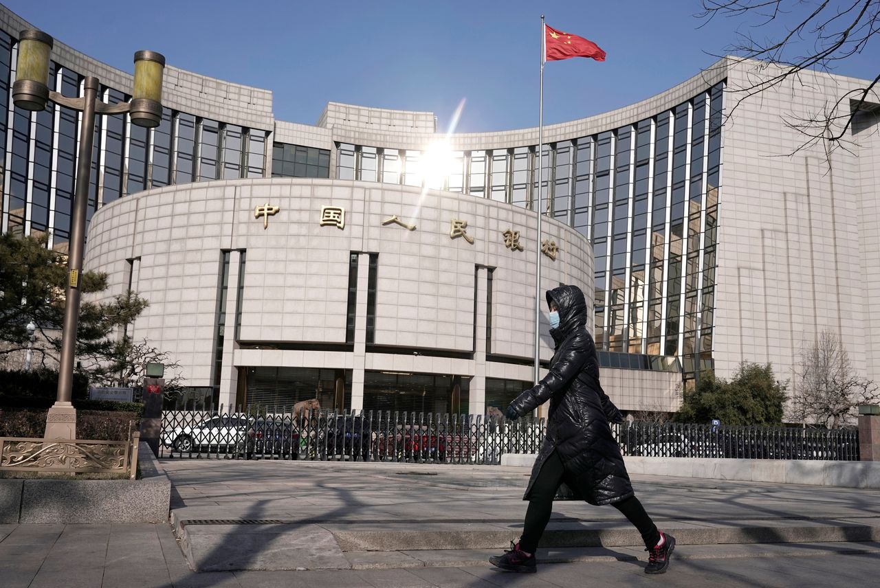 FILE PHOTO: A woman wearing a mask walks past the headquarters of the People