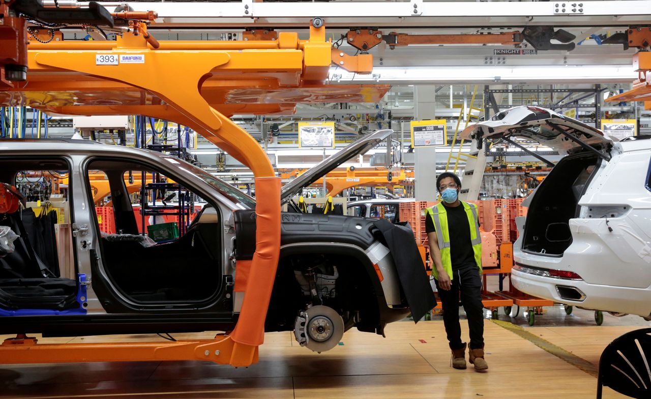 A Stellantis assembly worker walks between two 2021 Jeep Grand Cherokee L vehicles on the assembly line at the Detroit Assembly Complex - Mack Plant in Detroit, Michigan, U.S., June 10, 2021. Picture taken June 10, 2021. REUTERS/Rebecca Cook