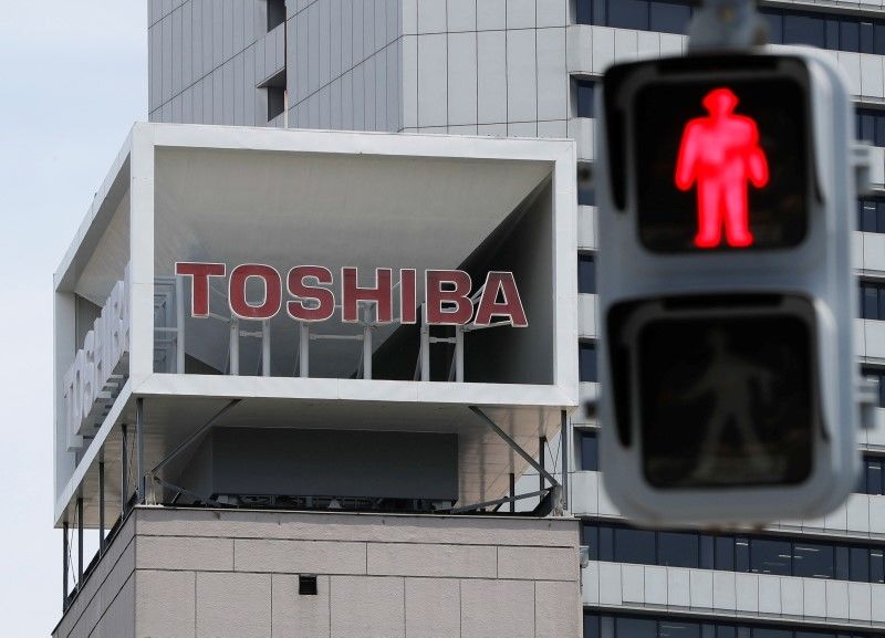 FILE PHOTO: The logo of Toshiba Corp. is seen next to a traffic signal atop of a building in Tokyo, Japan June 11, 2021. REUTERS/Issei Kato
