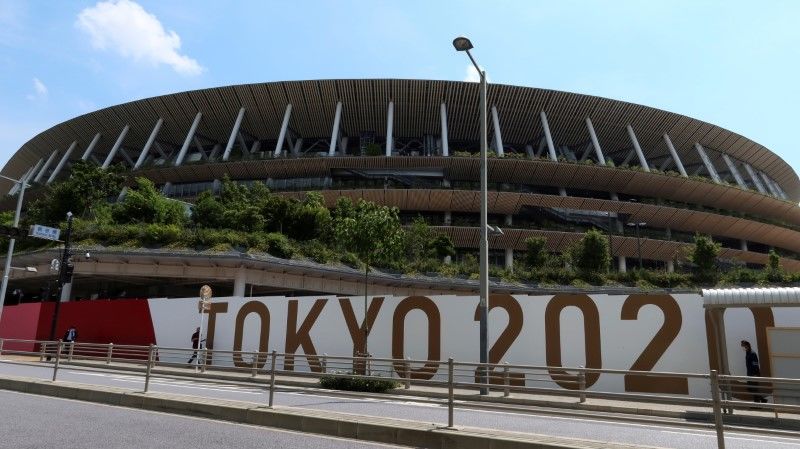 FILE PHOTO: People walk outside the security fence of Olympic Stadium (National Stadium) built for Tokyo Olympic Games, that have been postponed to 2021 due to the coronavirus disease (COVID-19) outbreak, in Tokyo, Japan June 11, 2021. REUTERS/Pawel Kopczynski/File Photo