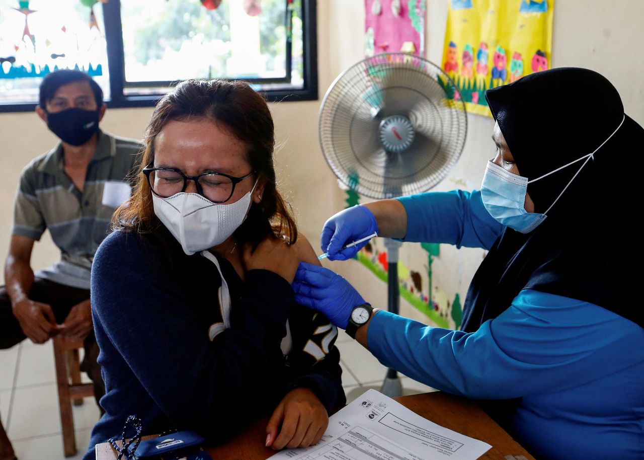FILE PHOTO: A woman wearing a protective mask reacts as she receives a dose of the AstraZeneca coronavirus disease (COVID-19) vaccine at a kindergarten in Jakarta, Indonesia, June 10, 2021. REUTERS/Ajeng Dinar Ulfiana/File Photo
