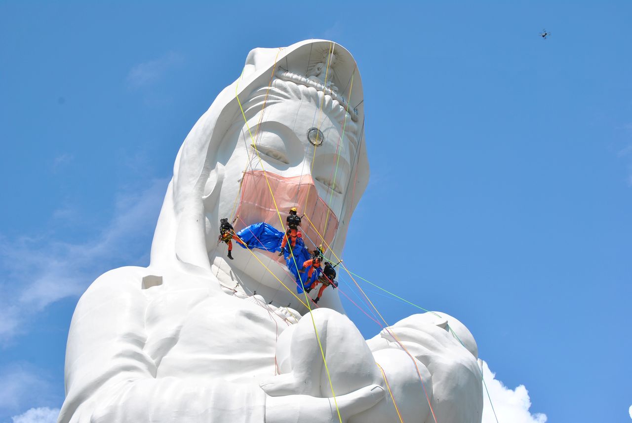 Workers place a mask on a 57-metre-high statue of Buddhist goddess Kannon to pray for the end of the coronavirus disease (COVID-19) pandemic at Houkokuji Aizu Betsuin temple in Aizuwakamatsu, Fukushima Prefecture, Japan in this handout photo taken on June 15 2021. Picture taken on June 15, 2021. Houkokuji Aizu Betsuin/Handout via REUTERS ATTENTION EDITORS - THIS IMAGE HAS BEEN SUPPLIED BY A THIRD PARTY. NO RESALES. NO ARCHIVES. MANDATORY CREDIT