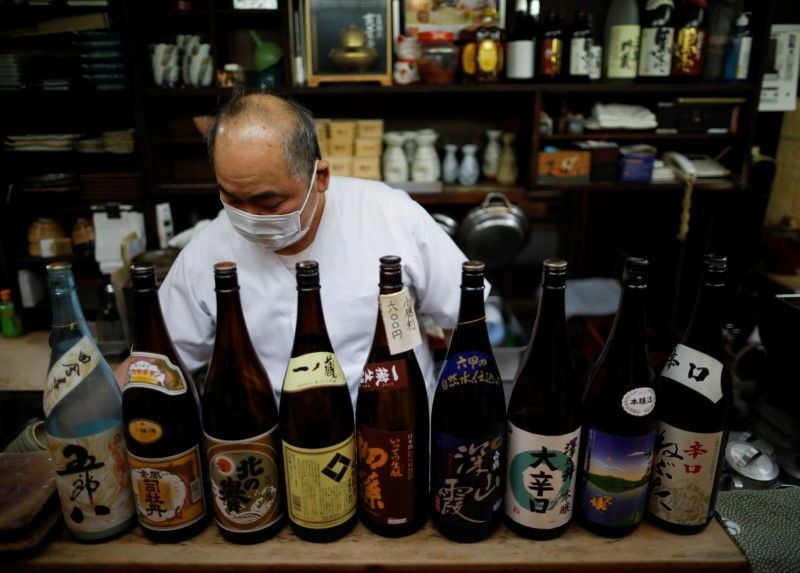 FILE PHOTO: The chef of an izakaya, a Japanese-style dining bar, prepares to close around 20:00 local time next to sake bottles, amid the coronavirus disease (COVID-19) outbreak, in Tokyo, Japan February 2, 2021. REUTERS/Issei Kato
