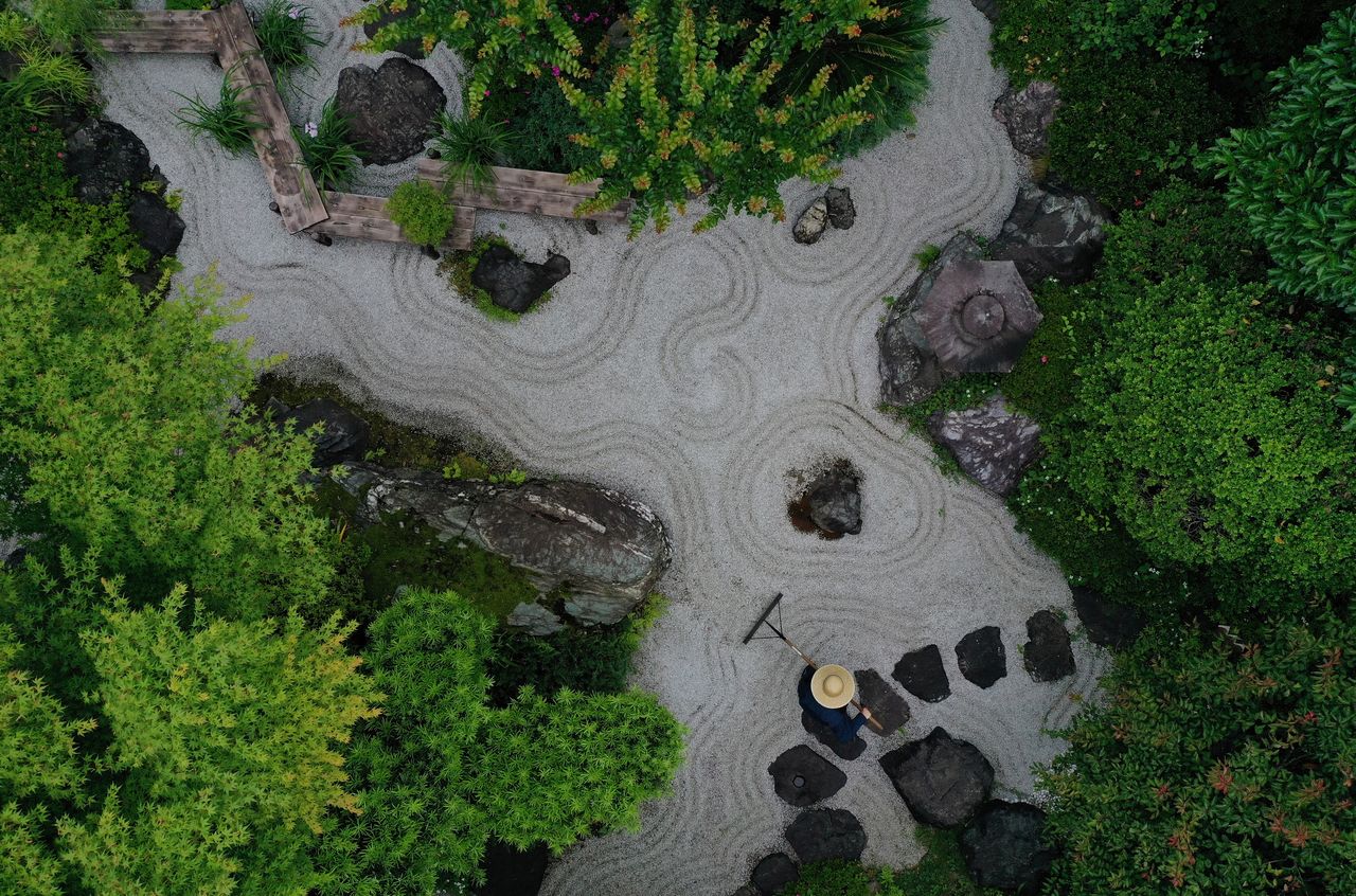 A gardener makes wave-shaped patterns, known as