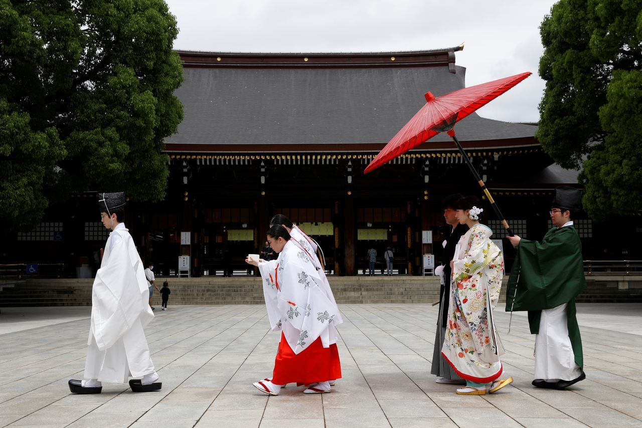 Shinto priests and shrine maidens guide a couple towards the wedding ceremony hall of Meijijingu shrine where the couple will get married in a traditional Japanese ceremony in Tokyo, Japan, June 5, 2021. REUTERS/Androniki Christodoulou