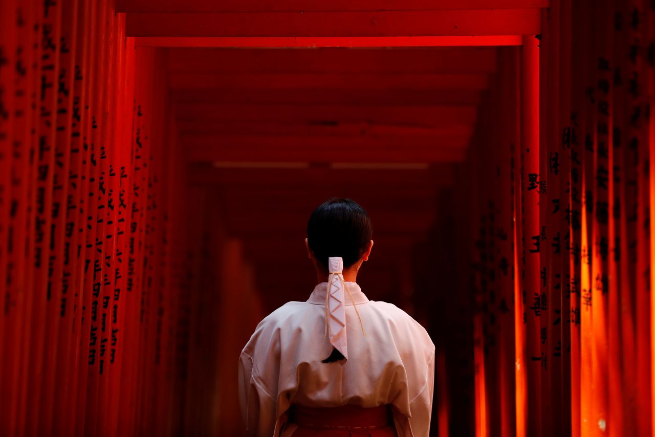 Shouko Totsuka, a Miko also known as a shrine maiden, poses for a photograph as she stands inside the tunnel of Red Torii Gate at the Hie-Jinja Shinto Shrine in Tokyo, Japan, June 1, 2021. REUTERS/Kim Kyung-Hoon