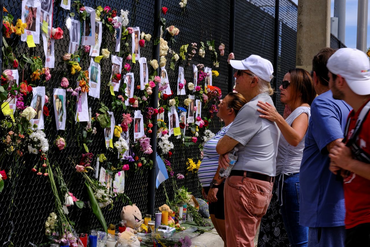 People mourn at the memorial site created by neighbors in front of the partially collapsed building where the rescue personnel continue their search for victims, in Surfside near Miami Beach, Florida, U.S., June 26, 2021. REUTERS/Maria Alejandra Cardona