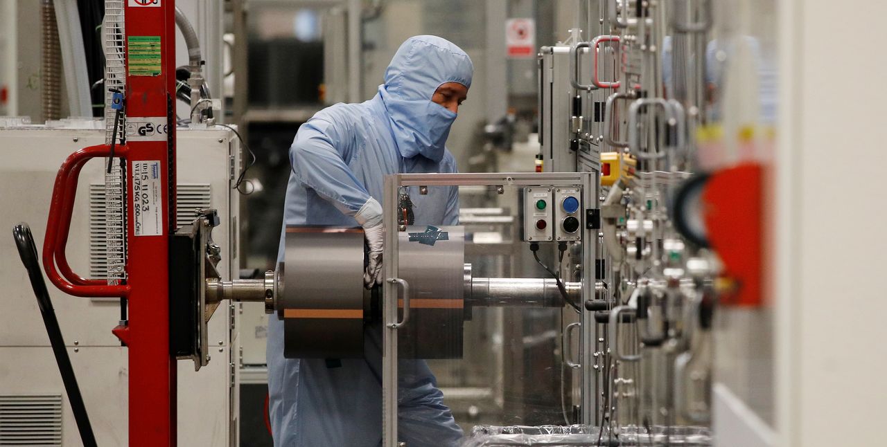 A worker in a protective suit operates a machine inside the Envision battery manufacturing plant at Nissan