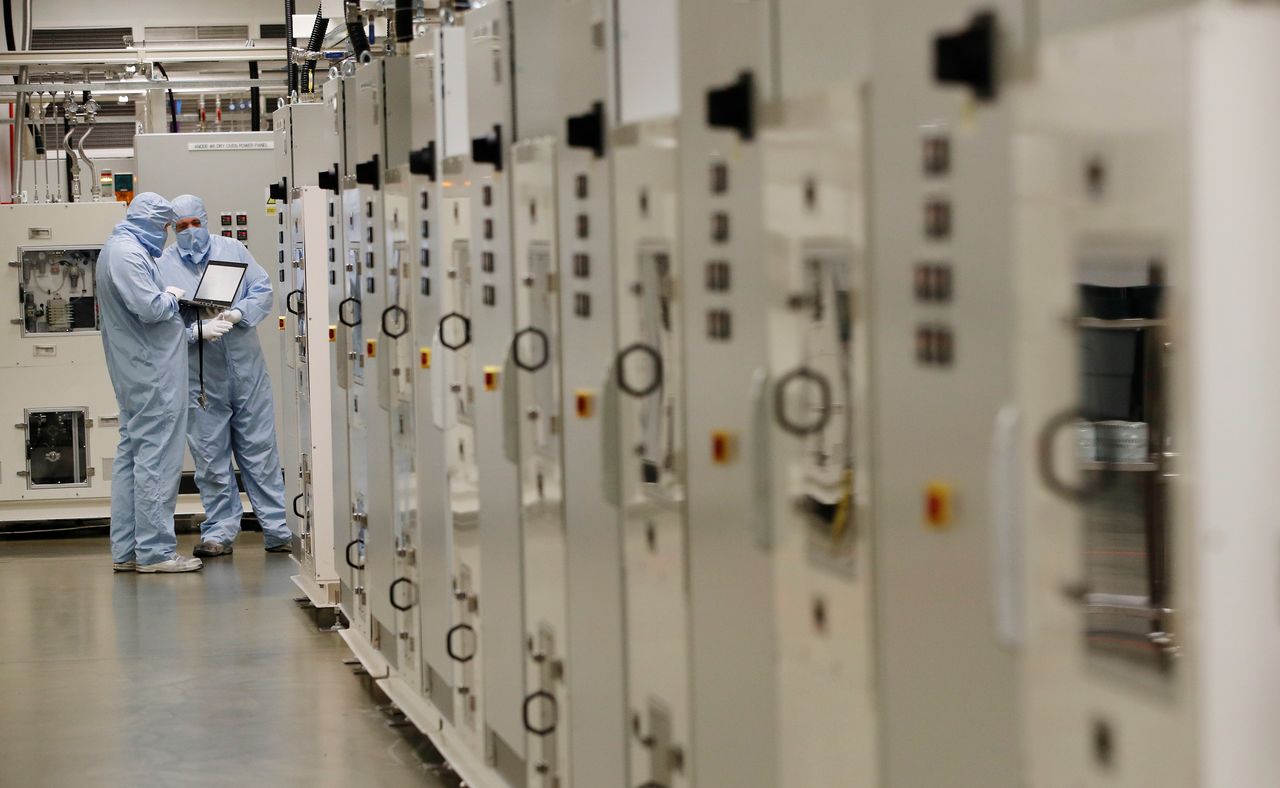Workers in protective suits check a computer inside the Envision battery manufacturing plant at Nissan