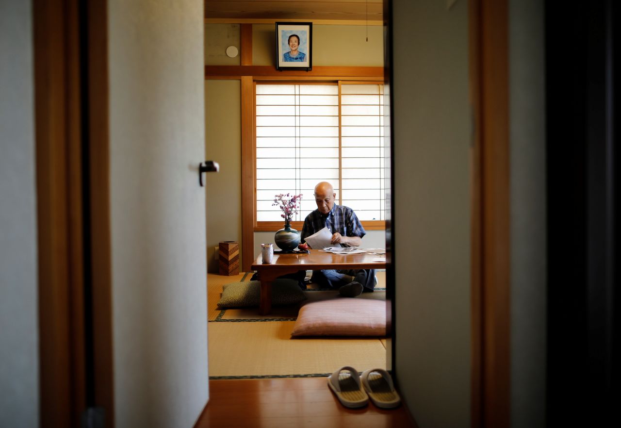 Kohei Jinno, 87, who was forced to leave his house two times ahead of the 1964 and 2020 Olympics Games to make way for construction of the main stadium, pauses under the portrait photo of his late wife Yasuko at his house, in Tokyo, Japan June 24, 2021. REUTERS/Issei Kato