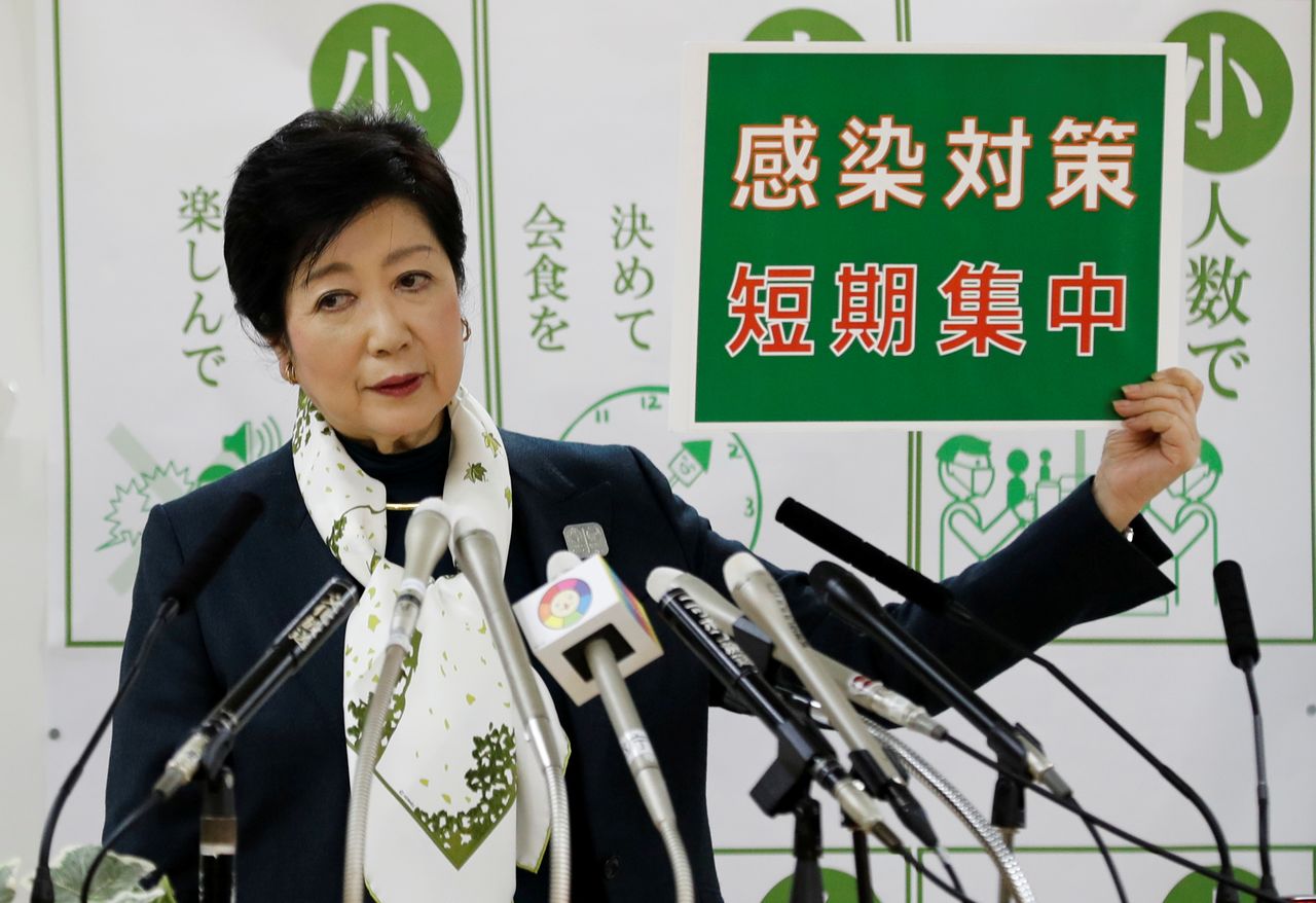 FILE PHOTO: Tokyo Governor Yuriko Koike holds a placard reading: "Short-term intensive infection control measure", a slogan about the city