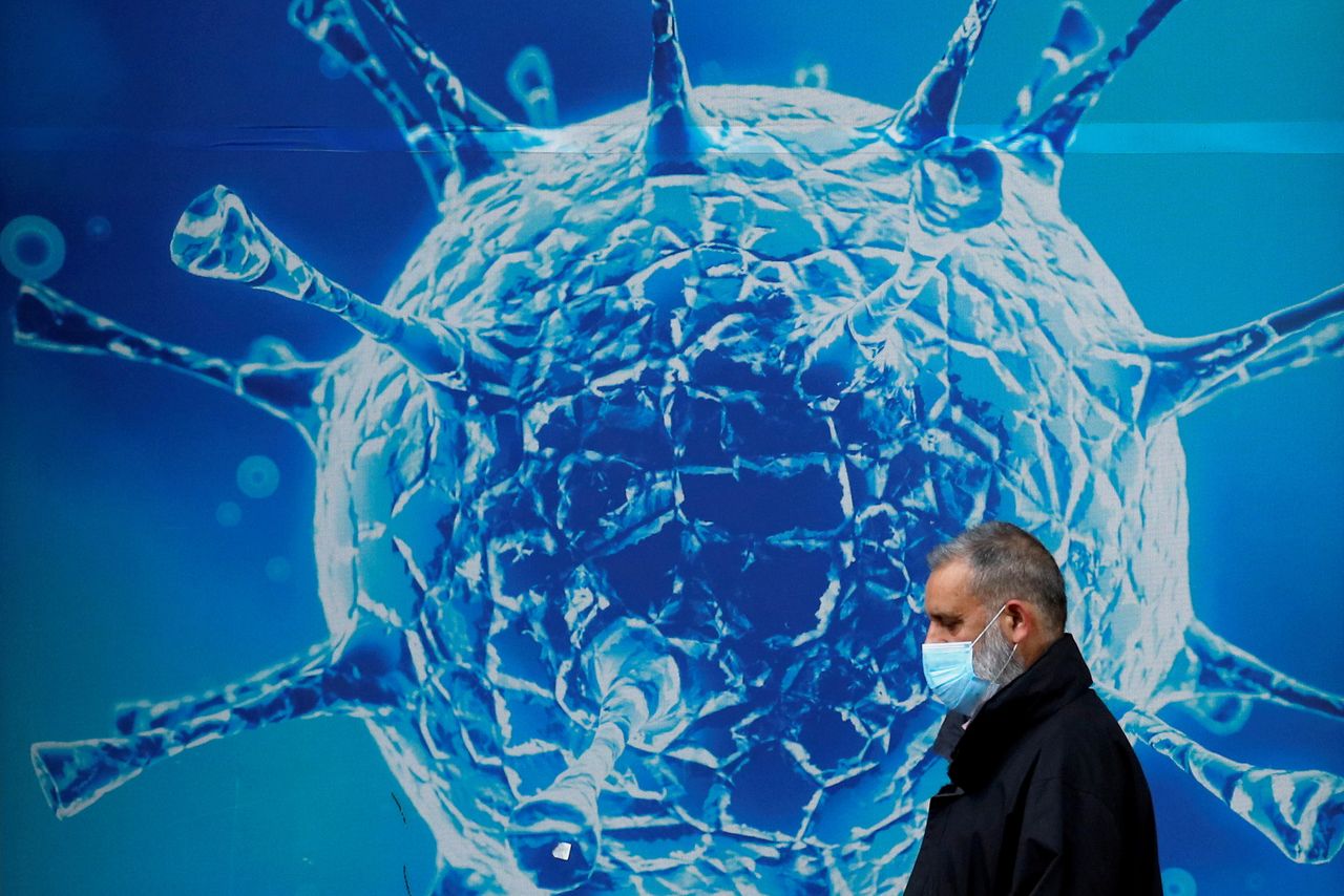 FILE PHOTO: A man wearing a protective face mask walks past an illustration of a virus outside a regional science centre amid the coronavirus disease (COVID-19) outbreak, in Oldham, Britain August 3, 2020. REUTERS/Phil Noble/File Photo