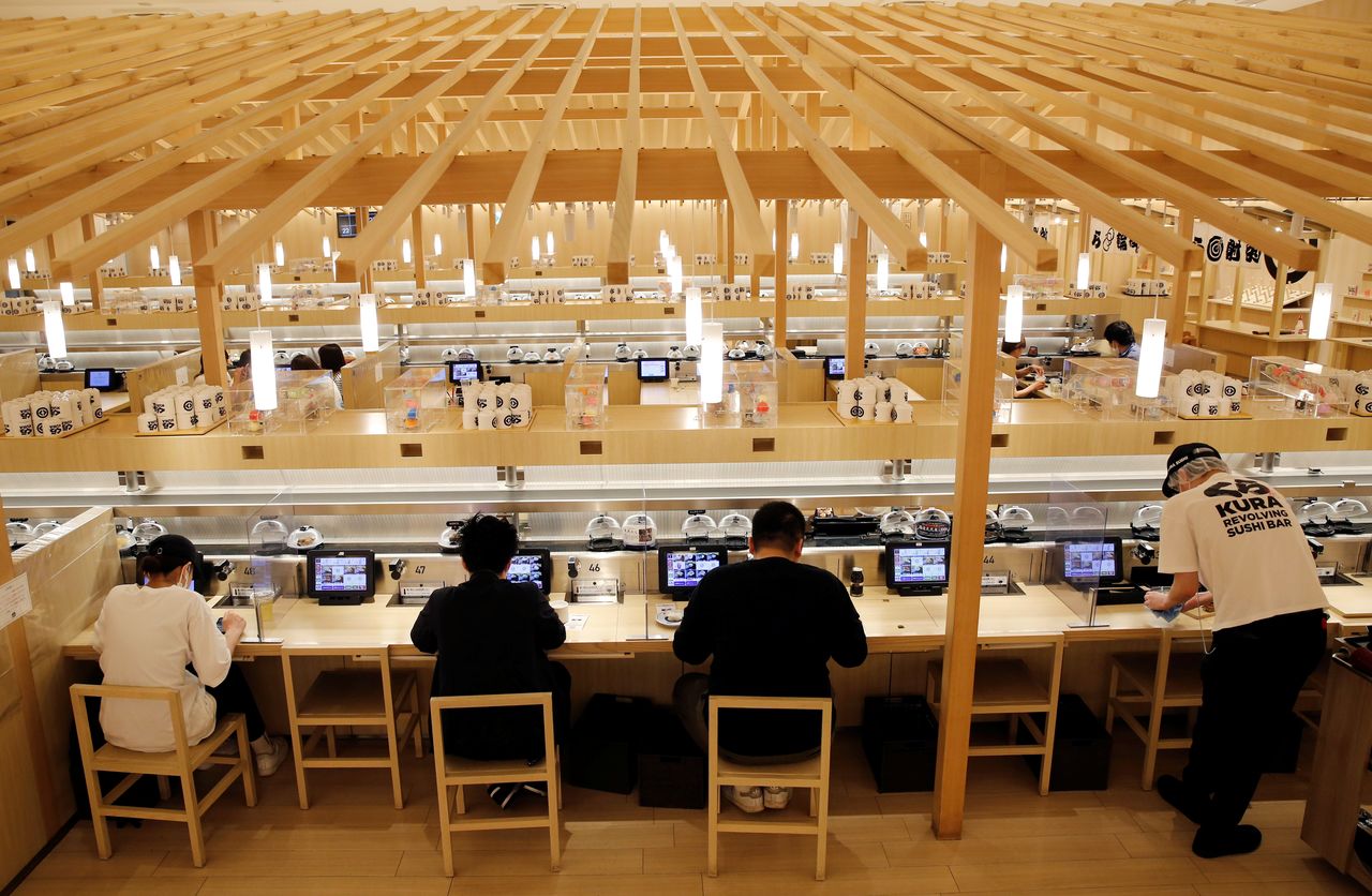 FILE PHOTO: Customers eat sushi off a conveyor belt at a Kura Sushi restaurant in Tokyo, Japan, June 3, 2021. REUTERS/Kim Kyung-Hoon