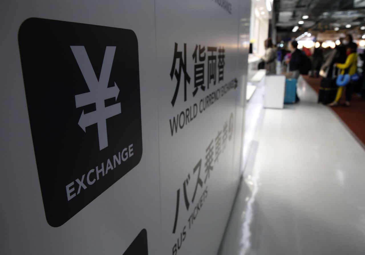 FILE PHOTO: A Japanese Yen currency sign (L) is seen at a currency exchange office as people line up to exchange money at Narita International airport, near Tokyo, Japan, March 25, 2016. REUTERS/Yuya Shino